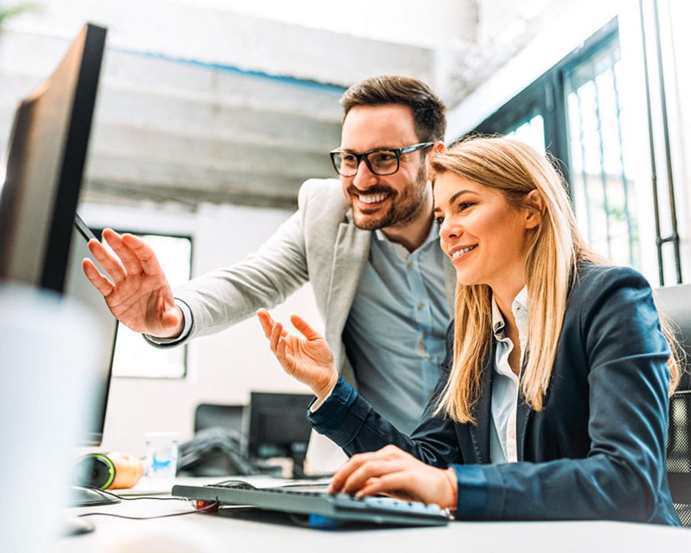 Ein Mitarbeiter und eine Mitarbeiterin aus dem Bereich Marktfolge bearbeiten gemeinsam eine Aufgabe.