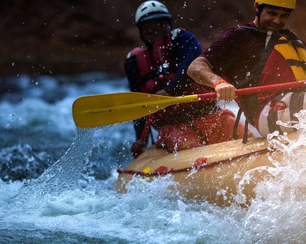 Personen beim Rafting in einem Fluss als Teambuilding Maßnahme