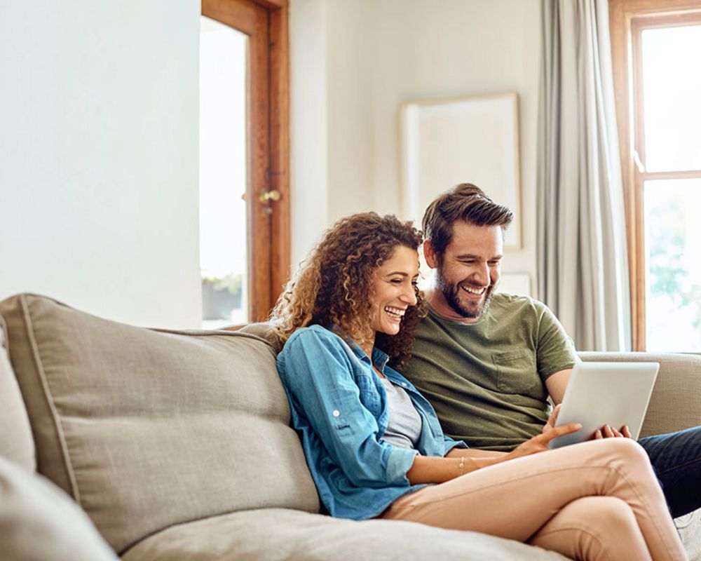 Ein Ehepaar sitzt auf dem Sofa und durchstöbert die digitalen Angebote der Sparkasse