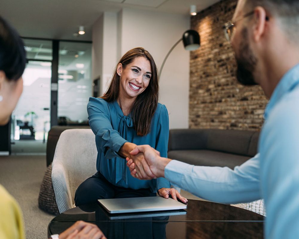 Eine Sparkassenfachwirtin begrüßt Kunden zu einem Kundengespräch