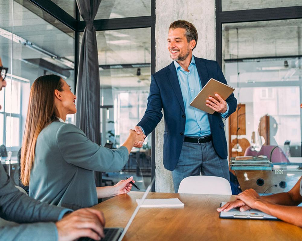 Teilnehmer/-innen eines Assessment Centers werden durch den Leiter des Assessment Centers begrüßt.