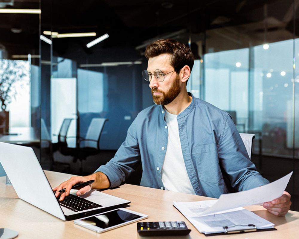 Ein Finanzexperte bearbeitet Unterlagen an seinem Schreibtisch